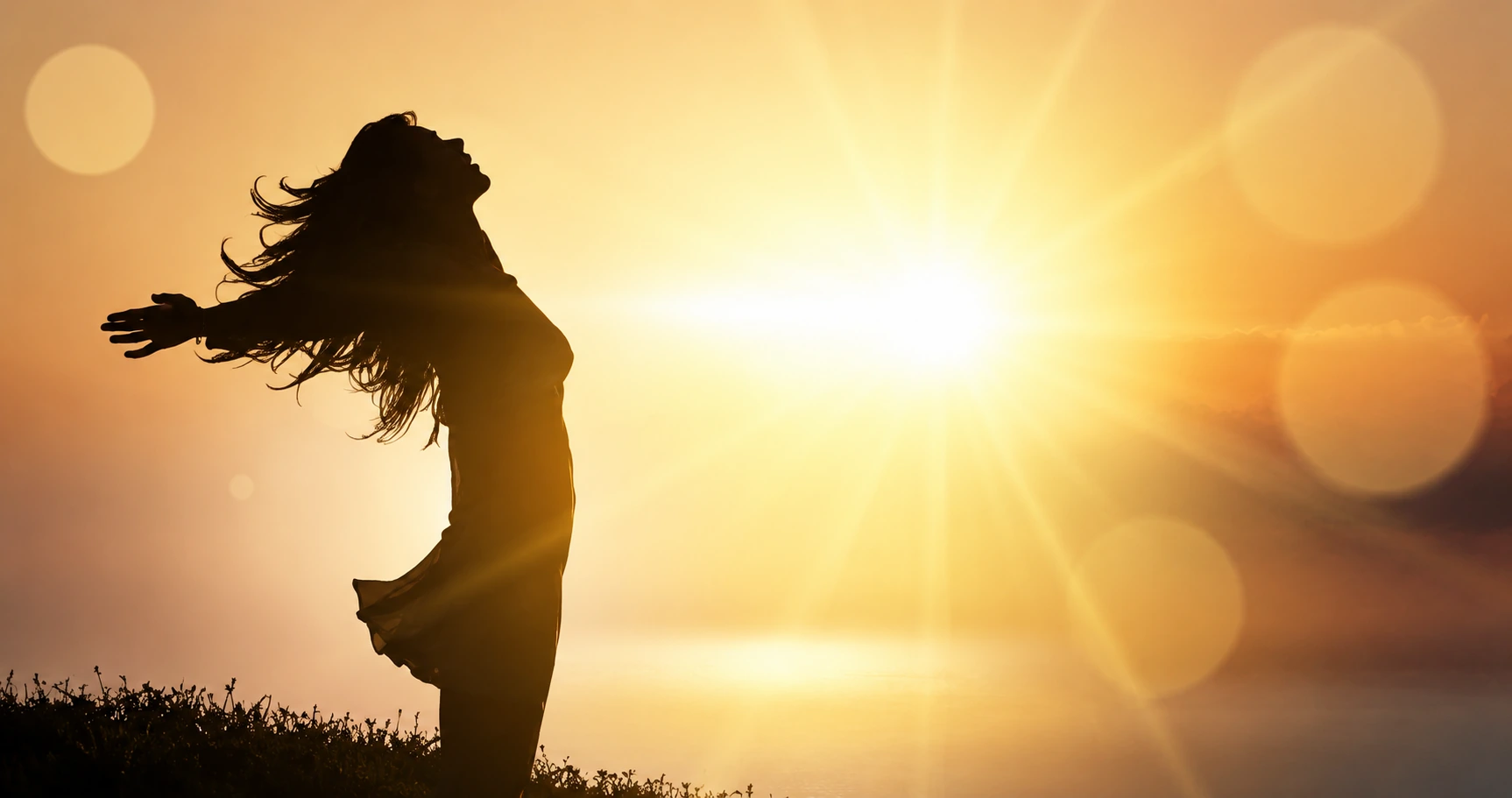 Woman with open arms facing the sunrise