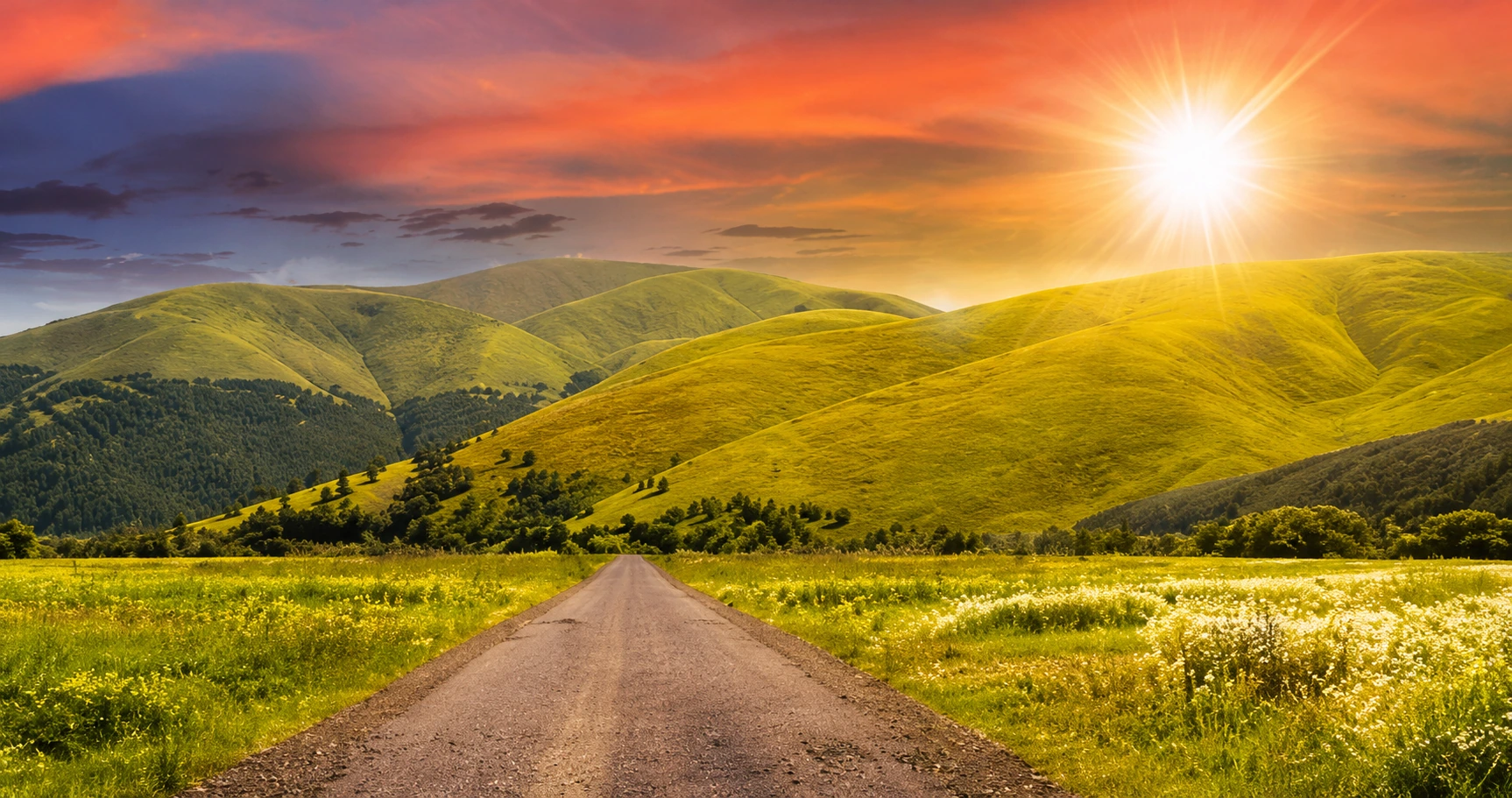 Country road toward sunlit hills at dawn